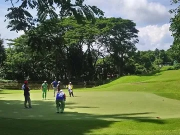 Iloilo Golf & Country Club のグリーンでプレーするゴルファーとキャディ